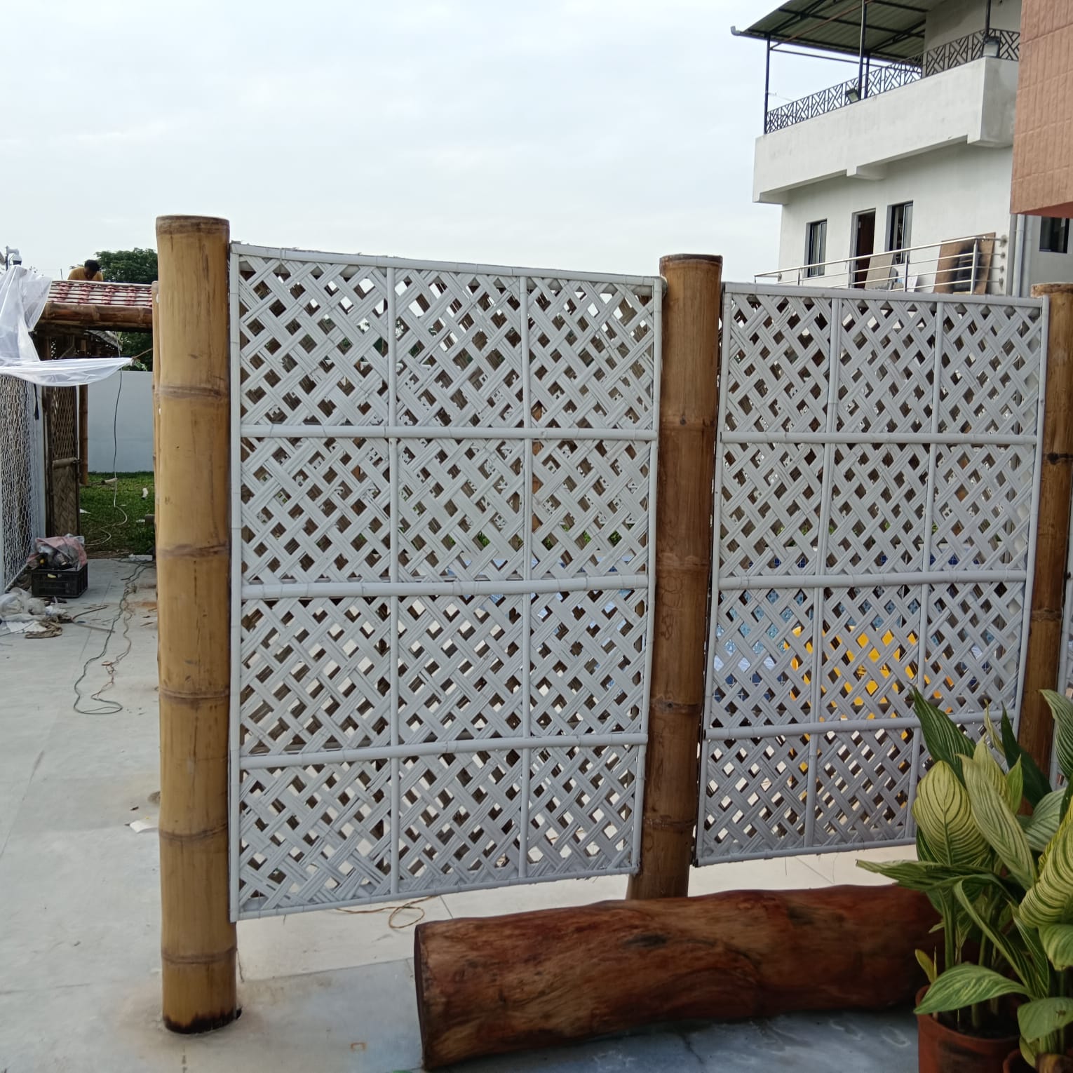 Woven bamboo lattice screens with wood log bench and plants