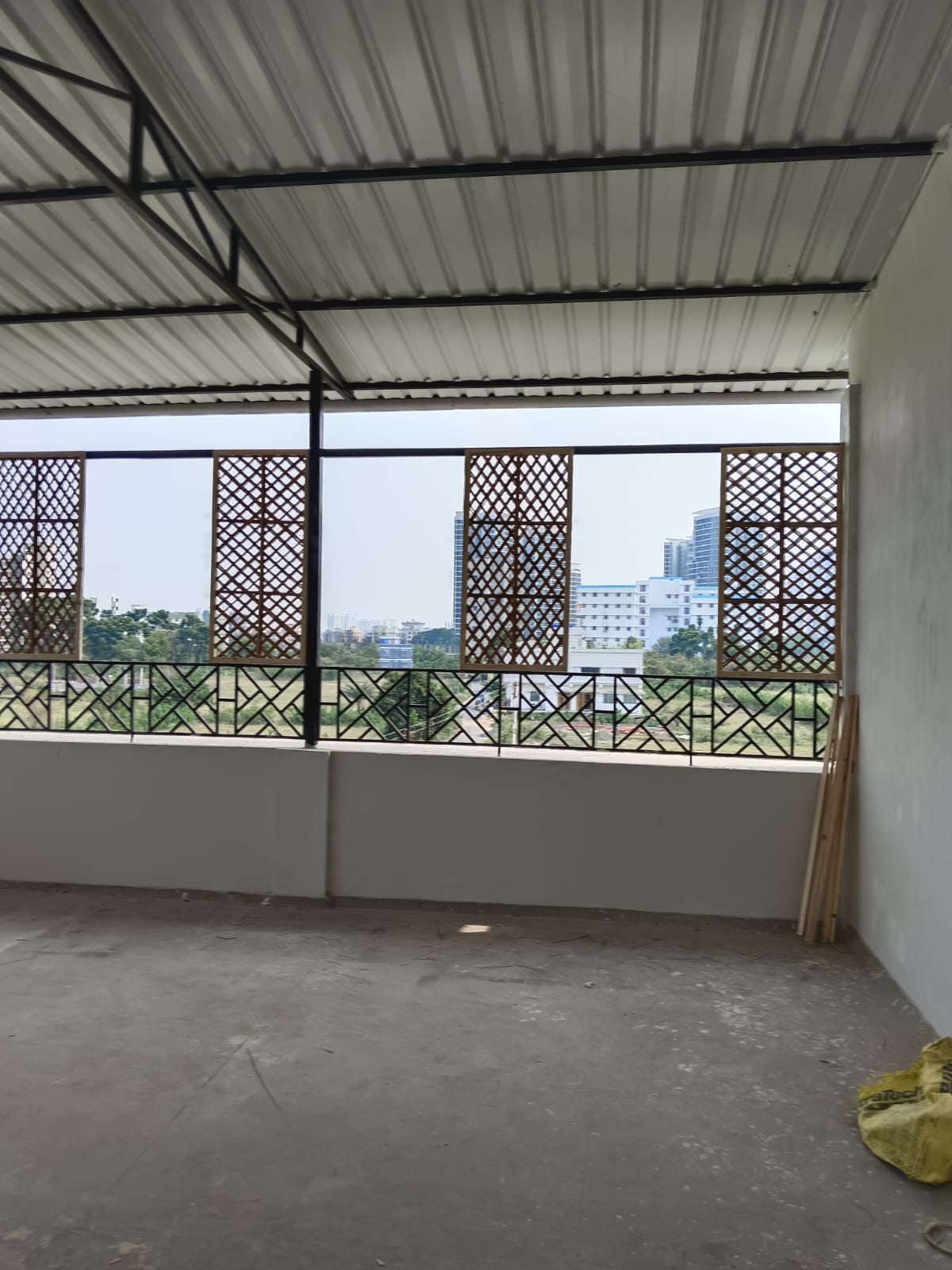 Cafe during construction: lattice screens installed on raw cement, no furniture